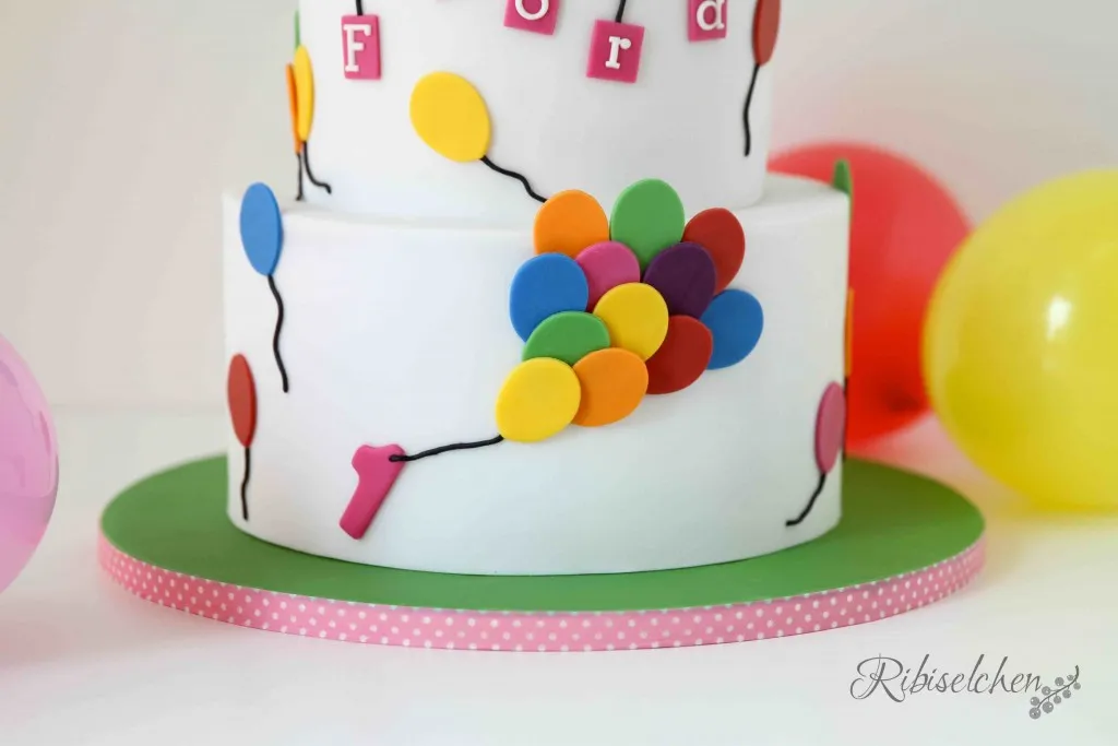 Die Zahl &quot;1&quot; aus Fondant auf dem Geburtstagskuchen mit Luftballons, symbolisch für den ersten Ehrentag