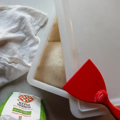 Dinkel-Pizzateig-Ballen nach der Ruhephase in einer Pizzaballenbox, bereit zum Ausrollen.