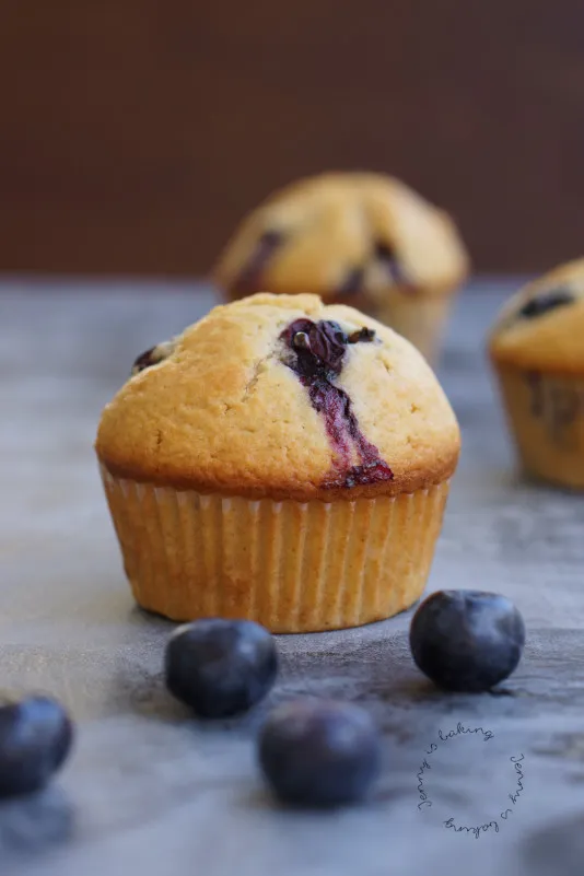 Drei appetitliche Heidelbeermuffins auf einem Holzbrett, die zum sofortigen Backen verführen.