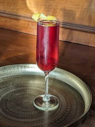 Drei kleine Gläser, gefüllt mit Crème de Cassis und Champagner, garniert mit Zitronenzesten