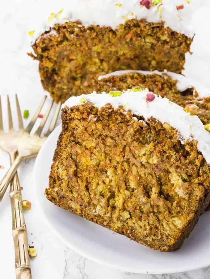 Drei Stücke saftiger veganer Karottenkuchen auf einem weißen Teller, bereit zum Genießen