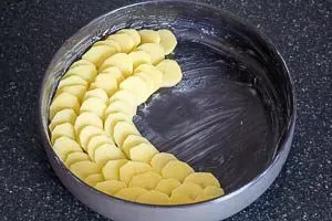 Dünn geschnittene Kartoffelscheiben werden dachziegelartig in eine Auflaufform geschichtet