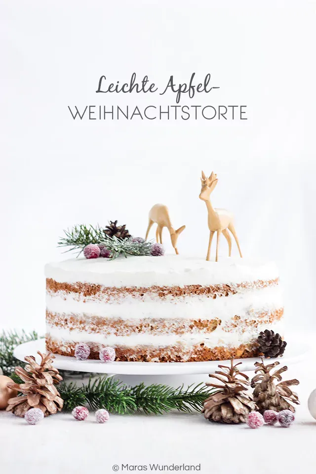 Ein angeschnittenes Stück gesunde Apfel Weihnachtstorte mit sichtbaren Schichten von Biskuit, Apfelkompott und Quarkcreme.