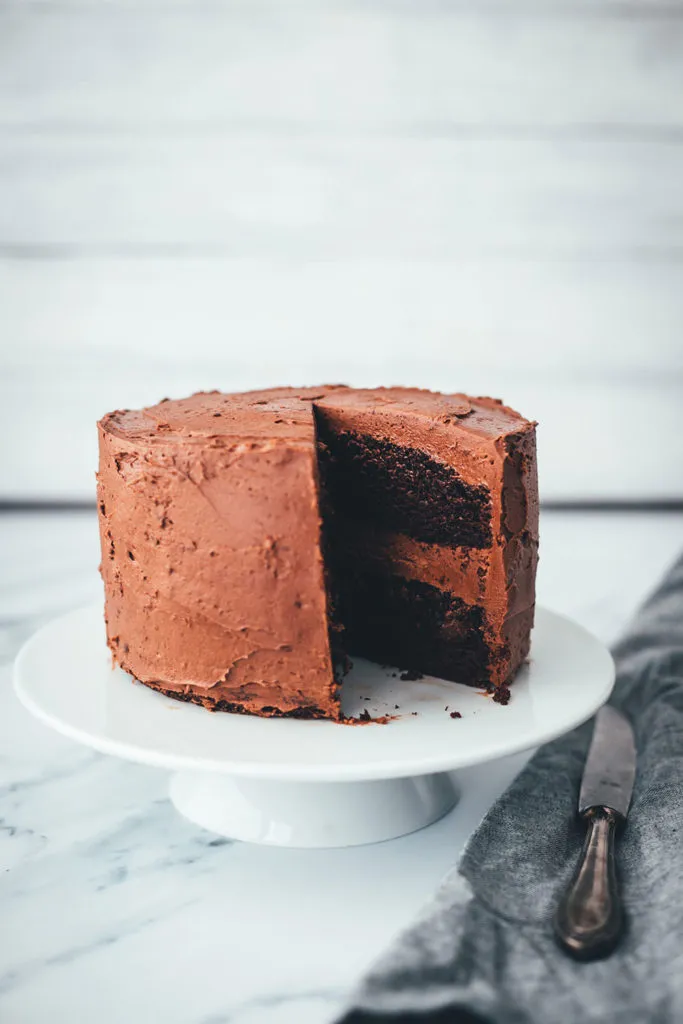 Ein Anschnitt des Schokokuchens mit Schoko-Frosting, der seine saftige Textur und die dicke Cremeschicht zeigt.