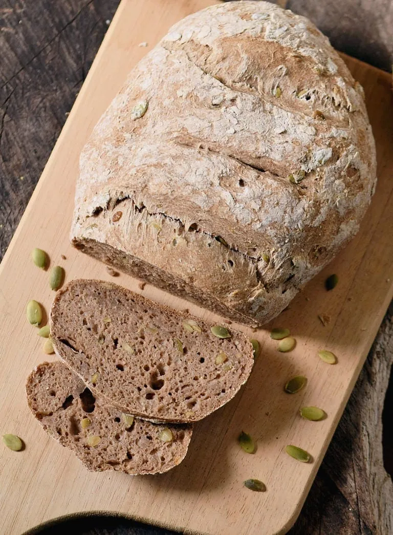 Ein Anschnitt eines hausgemachten glutenfreien Brotes, reich an Samen und mit einer luftigen Krume