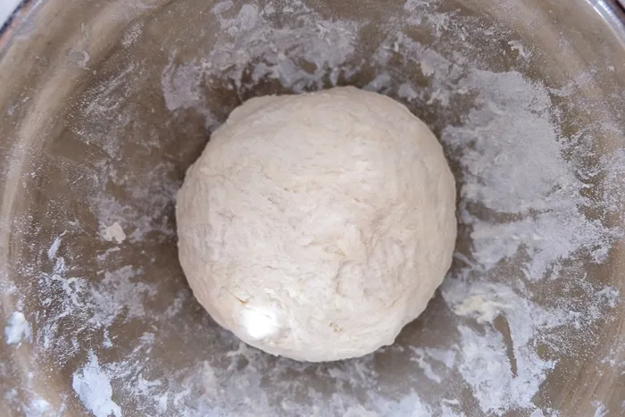 Ein Ball Brötchenteig in einer silbernen Rührschüssel