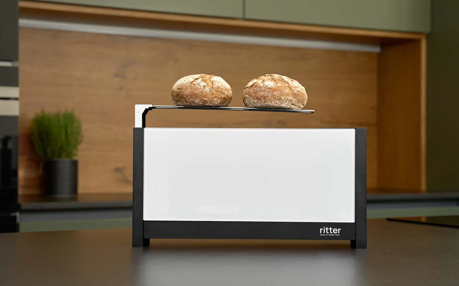 Ein Bild eines weißen Toasters, der Brote auf der Brötchenauflage liegen hat und auf einer Küchenplattform steht.