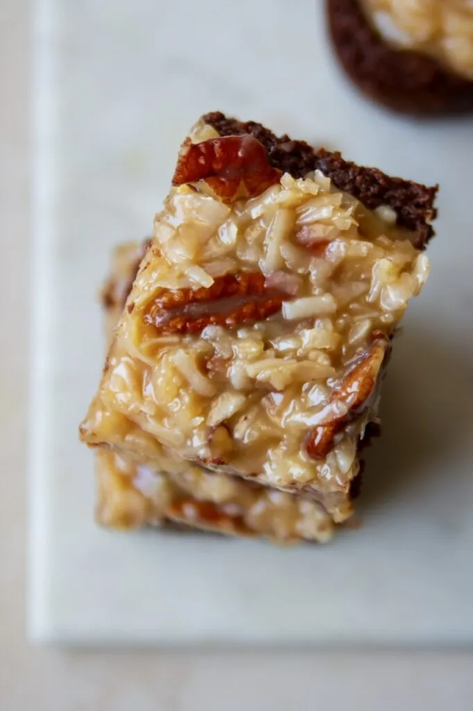 Ein Blech mit fertig gebackenen veganen Brownies, die mit einem Messer mit Wellenschliff in Quadrate geschnitten werden.