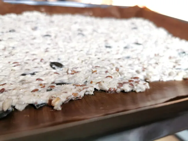 Ein Blech mit frisch gebackenem Knäckebrot, das bereits in einzelne Stücke geschnitten wurde, wobei die goldbraune Farbe und die sichtbaren Körner die Knusprigkeit betonen.