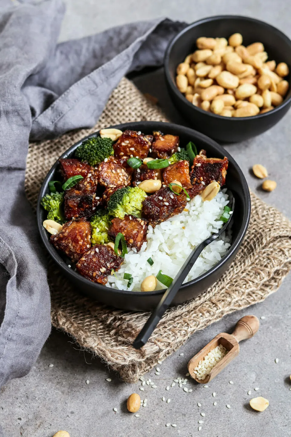 Ein Block Räuchertofu auf einem Holzbrett, umgeben von frischen Kräutern und Gewürzen.