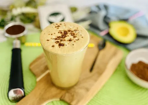 Ein cremiger Avocado-Kaffee-Smoothie mit Eiswürfeln und Kaffeebohnen