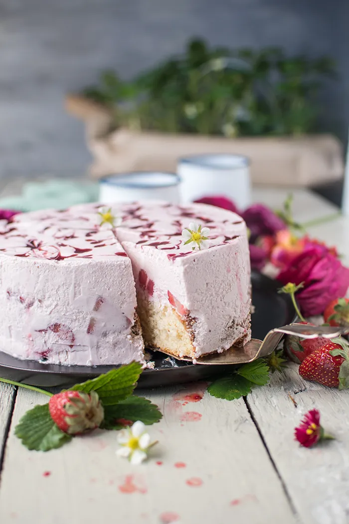 Ein Detailfoto zeigt die kunstvollen Erdbeerwirbel auf der Erdbeer Joghurt Sahne Torte, die mit einem Holzstäbchen in die Joghurtcreme gezogen wurden und ein ansprechendes Muster bilden.