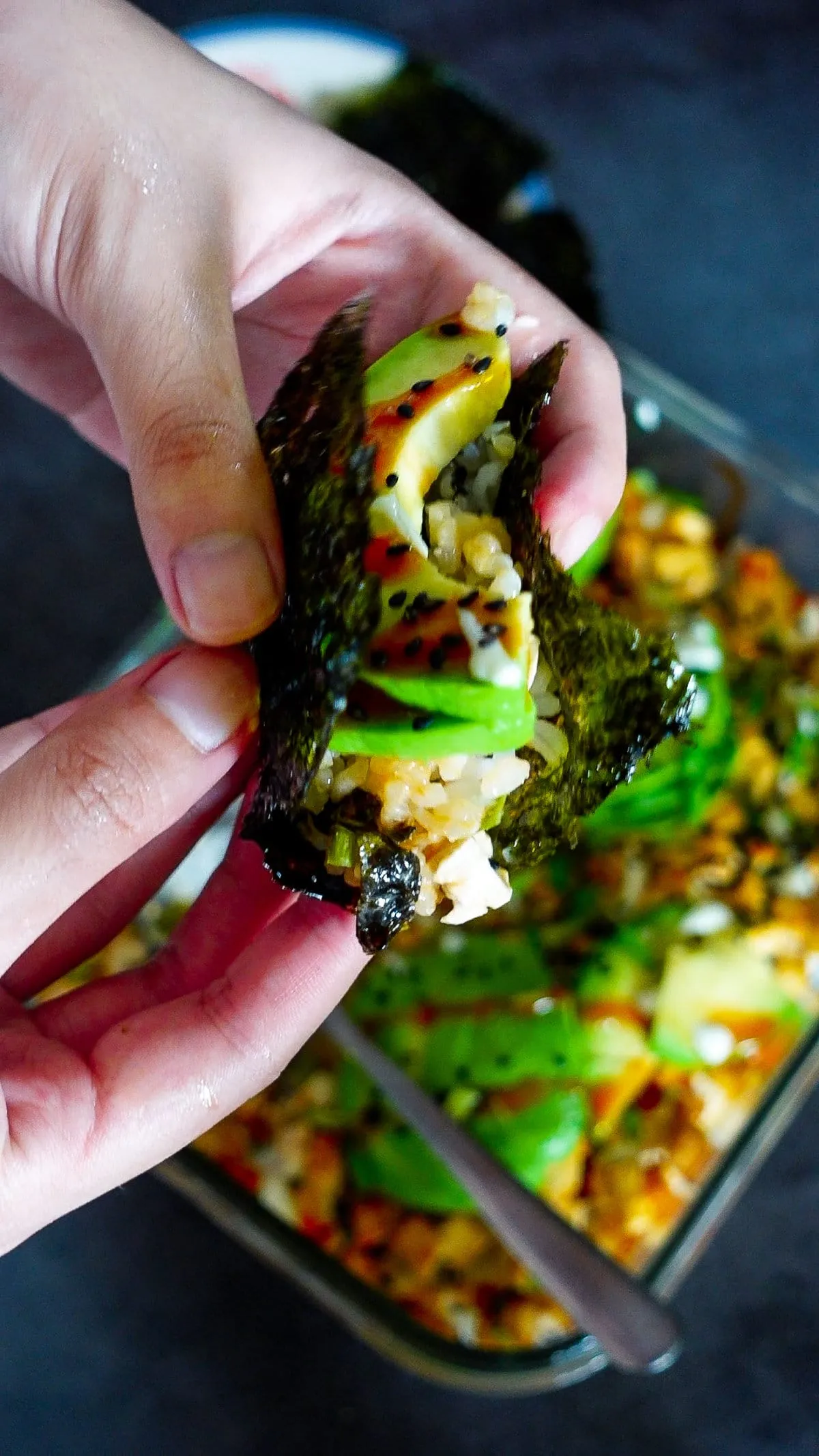 Ein einzelner Biss des Vegan Sushi Auflaufs, umhüllt von Nori, mit allen köstlichen Schichten