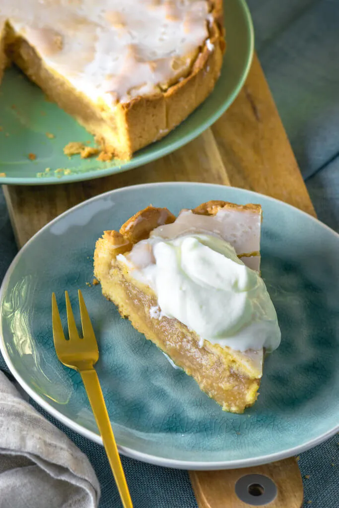 Ein frisch gebackener gedeckter Apfelkuchen mit Apfelmus, serviert mit einem großzügigen Klecks Schlagsahne, purem Genuss