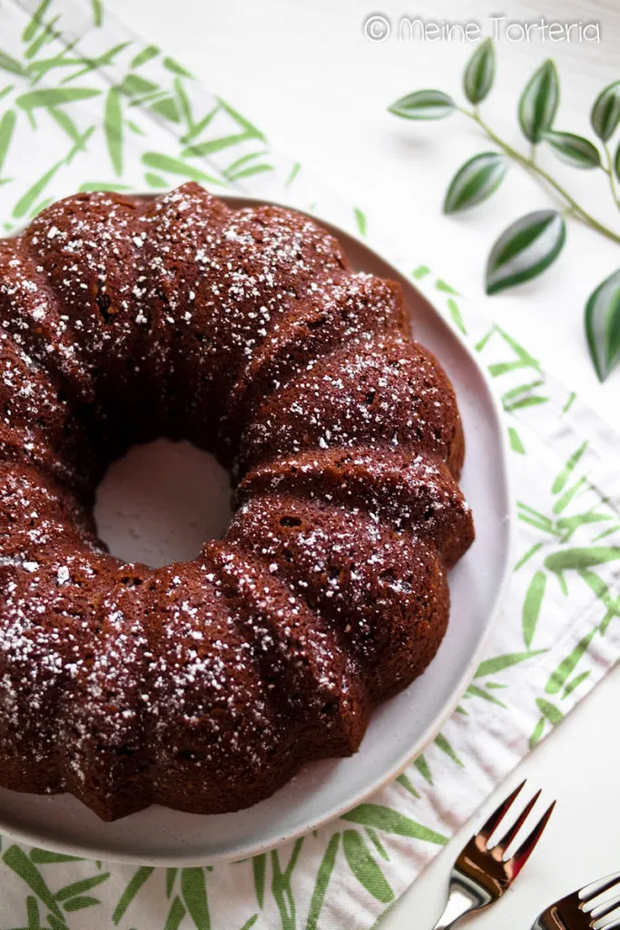 Ein frisch gebackener Gugelhupf mit Paradiescreme, zart bestäubt mit Puderzucker auf einer eleganten Etagere