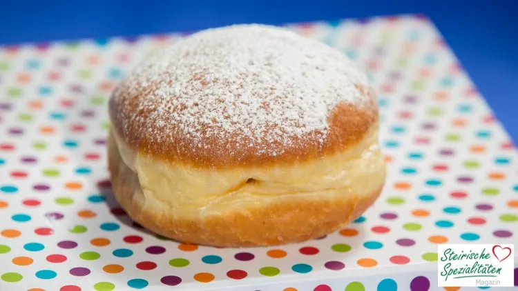 Ein frisch gebackener Krapfen mit Puderzucker bestreut und Aprikosenmarmelade gefüllt, bereit zum Genuss.