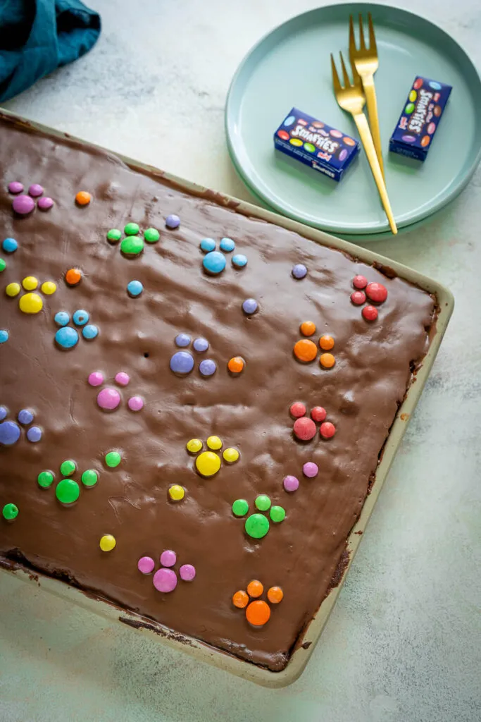 Ein frisch gebackener, marmorierter Blechkuchen mit leuchtenden Smarties in Paw Patrol Farben, detailreich und appetitlich.