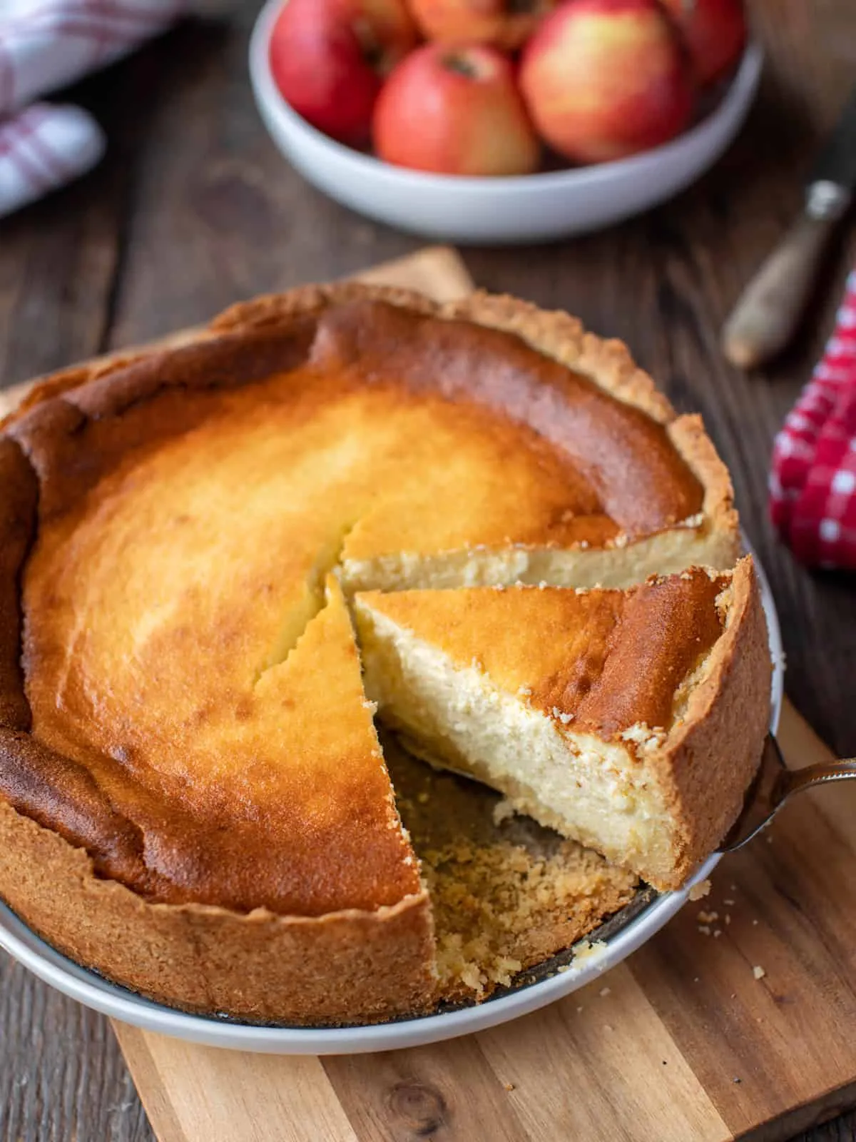 Ein ganzer, goldbraun gebackener deutscher Käsekuchen mit Quark auf einem Servierbrett