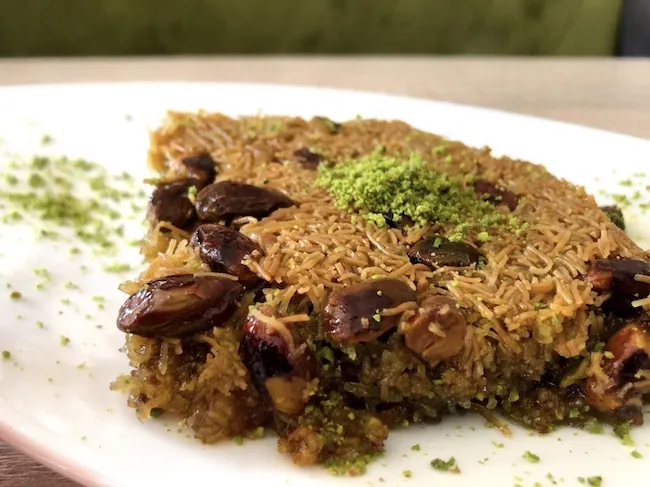 Ein gemütliches Café mit Holztischen und Stühlen, das zum Verweilen im Öz-Tat Café Baklava Bäckerei einlädt