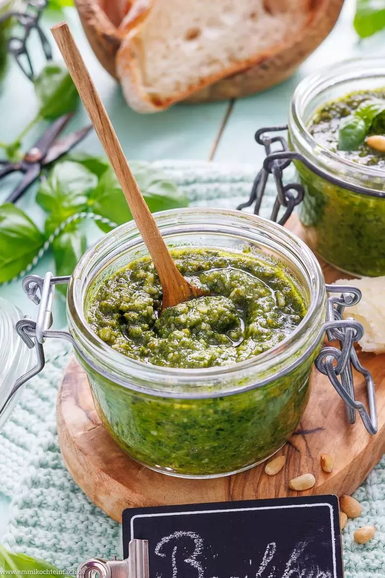 Ein geöffnetes Glas grünes Pesto Genovese, bedeckt mit einer Schicht Olivenöl zur Haltbarkeit