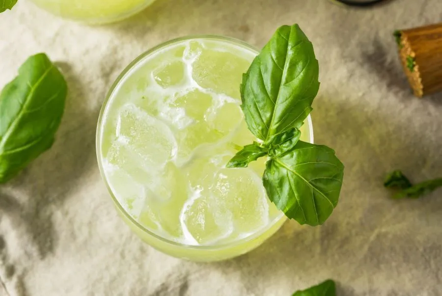 Ein Glas mit Gin Basil Smash, garniert mit frischen Basilikumblättern und Eiswürfeln