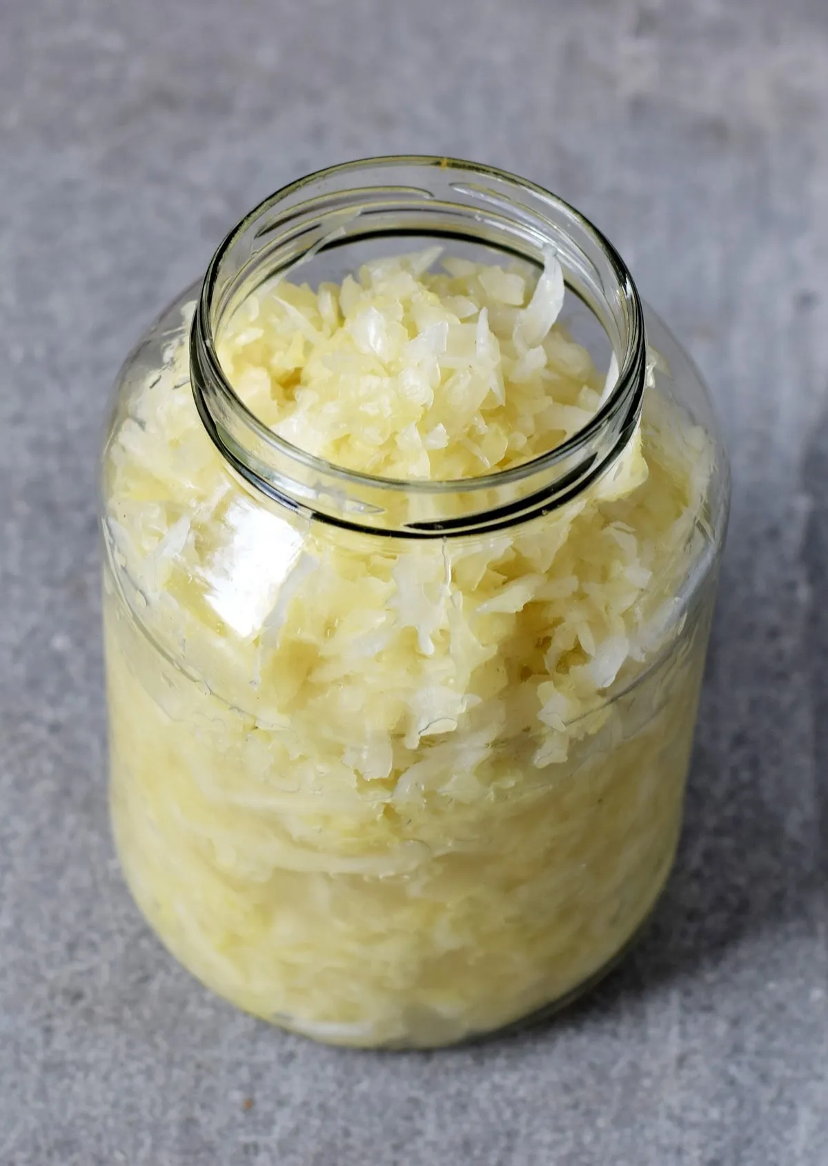 Ein Glas selbstgemachtes, goldgelbes Sauerkraut, frisch fermentiert und bereit zum Genuss, symbolisiert die deutsche Esskultur.