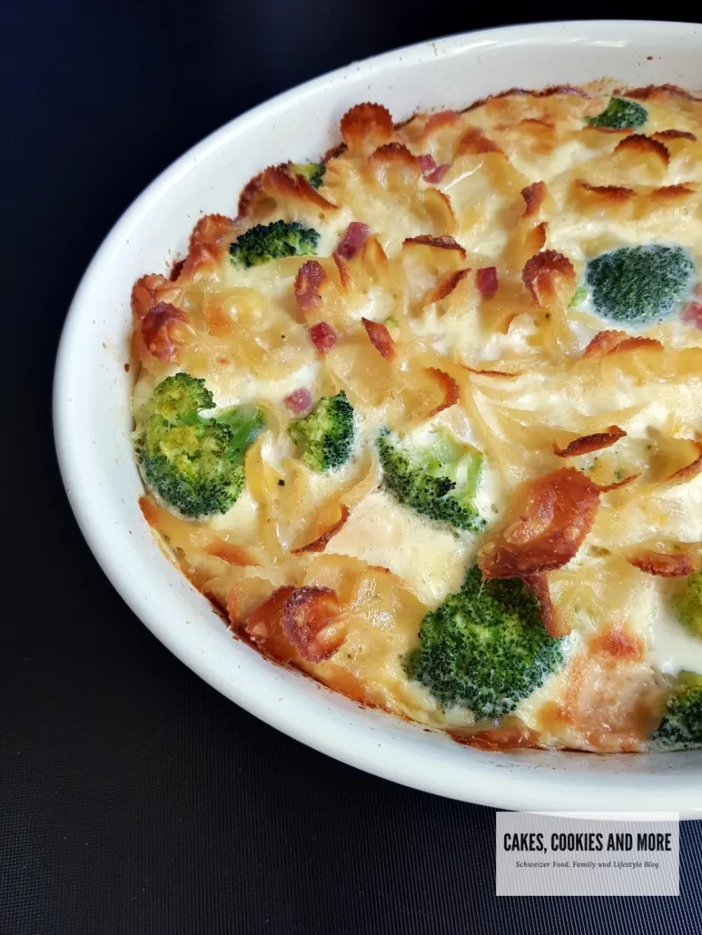 Ein goldbraun gebackener Teigwaren-Auflauf mit Käse überbacken auf einem Holztisch, bereit zum Servieren.
