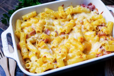 Ein goldbraun überbackener Nudel-Schinken-Auflauf in einer Keramikauflaufform, bereit zum Servieren, mit cremigem Käse und Nudeln