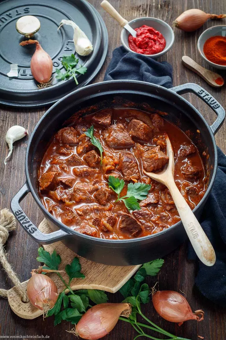 Ein großer Topf mit köstlichem Rindergulasch, das langsam auf dem Herd schmort, ein Klassiker der deutschen Küche.