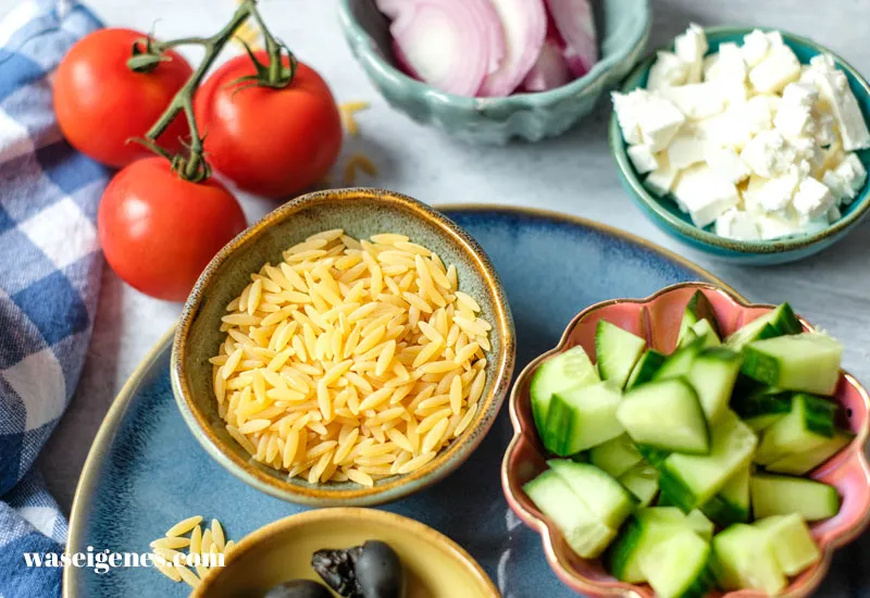 Ein hoher Becher mit Zutaten für das Dressing: Olivenöl, Zitronensaft, Knoblauch und Oregano, bereit zum Mixen.
