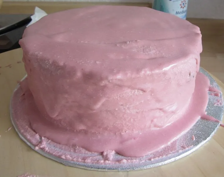 Ein hoher Kuchen, der geschichtet wird, mit einem Spatel, der die Creme glättet