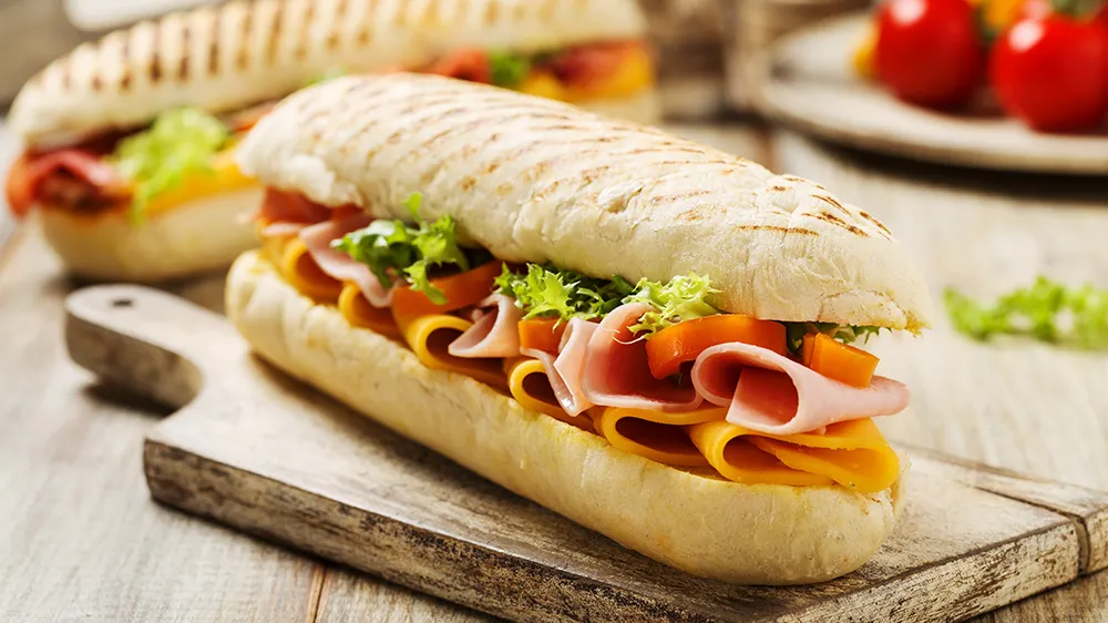 Ein italienisches Panini gefüllt mit Schinken, Käse und frischem Salat, knusprig gegrillt.