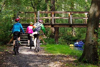 Ein Kanu liegt bereit am Ufer eines Spreewaldfließes neben Fahrrädern, ideal für einen Kombi-Urlaub mit Rad und Kanu.