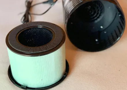 Ein kompakter, weißer Luftreiniger, speziell für den Einsatz im Kühlschrank konzipiert, wird auf einem Kühlschrankregal platziert.