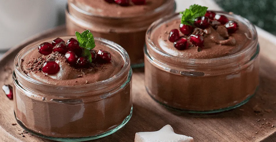 Ein kunstvoll angerichtetes Schokoladenmousse mit Beeren und Minze, präsentiert als elegantes Dessert in einem traditionellen deutschen Gasthaus.