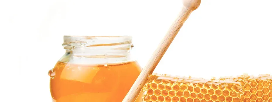 Ein Löffel voller goldenem Honig, der Süße und Linderung in heißer Milch bei einem trockenen, kratzenden Hals bietet.