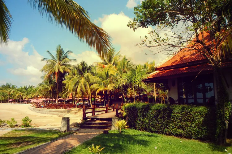 Ein malerischer Strand in Khao Lak, Thailand, mit Palmen und traditionellen Longtail-Booten