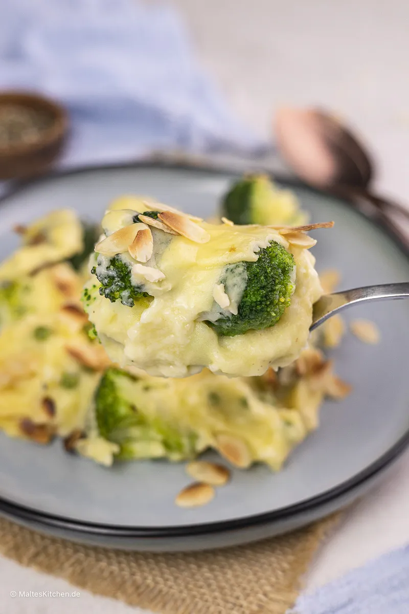 Ein Nahaufnahme-Bild eines köstlichen Kartoffelbrei-Auflaufs mit Brokkoli, der dampfend aus dem Ofen kommt.