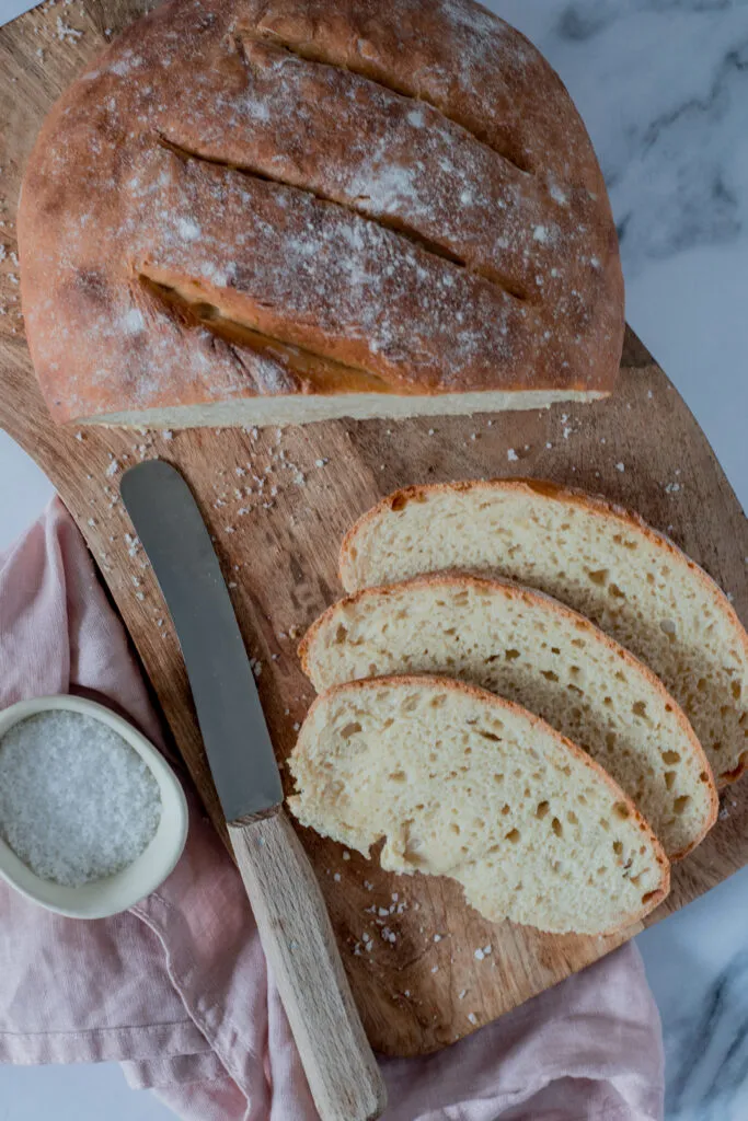Ein perfekt gebackenes, einfaches Brot liegt auf einem Holztisch.