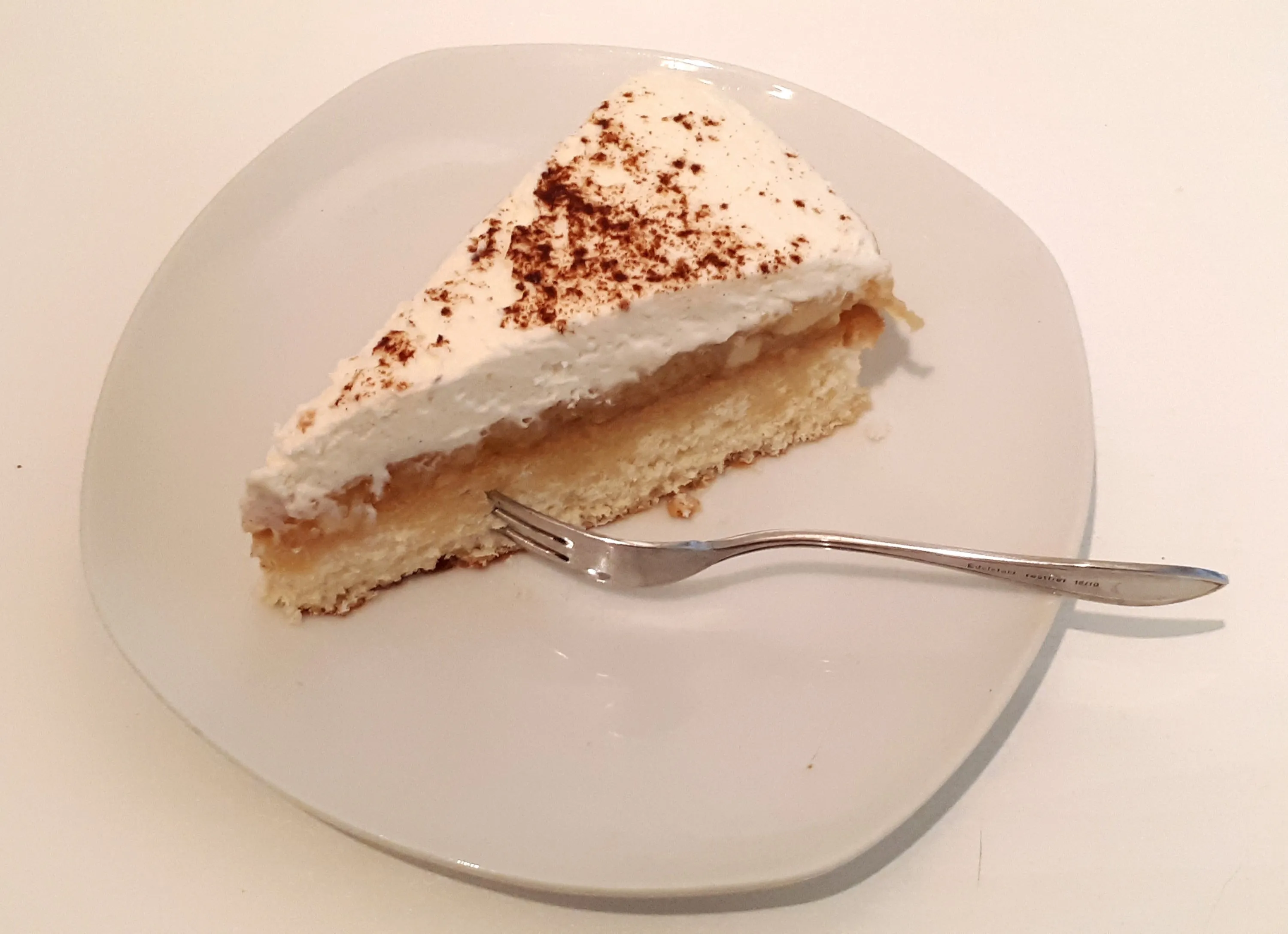 Ein perfektes Stück Zimt-Quark-Sahne-Torte mit sichtbaren Schichten aus Biskuit, Apfelfüllung und cremiger Zimt-Quark-Sahne.