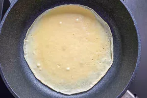 Ein Pfannkuchen brät in der Pfanne und stockt, bevor er gewendet wird, um eine perfekte Bräunung zu erzielen.