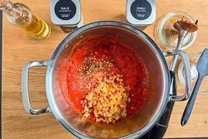 Ein Pürierstab zerkleinert das geröstete Gemüse im Topf zu einer cremigen Ajvar-Paste