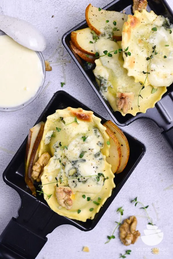Ein Raclette Pfännchen mit selbstgemachten Ravioli, Birnenspalten und zerflossenem Gorgonzola, eine ausgefallene vegetarische Raclette Idee.