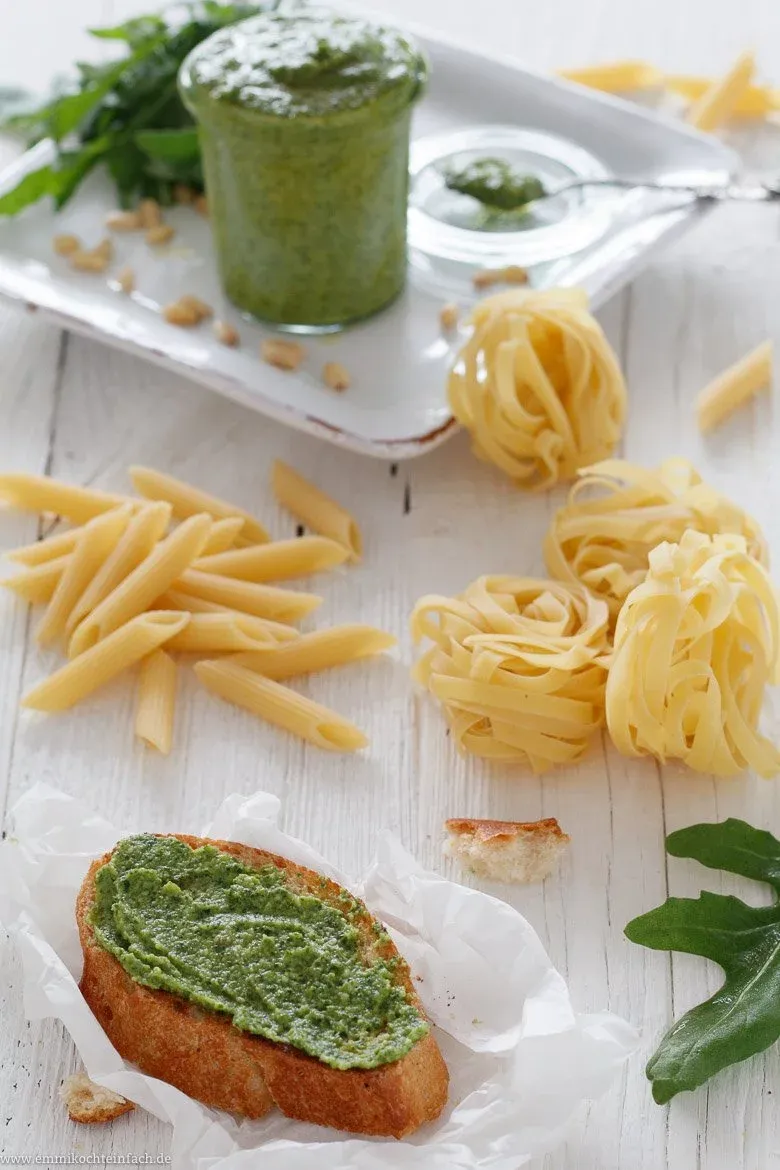 Ein reichlich belegter Teller mit Crostini oder Bruschetta, garniert mit Rucola Pesto und frischem Rucola.