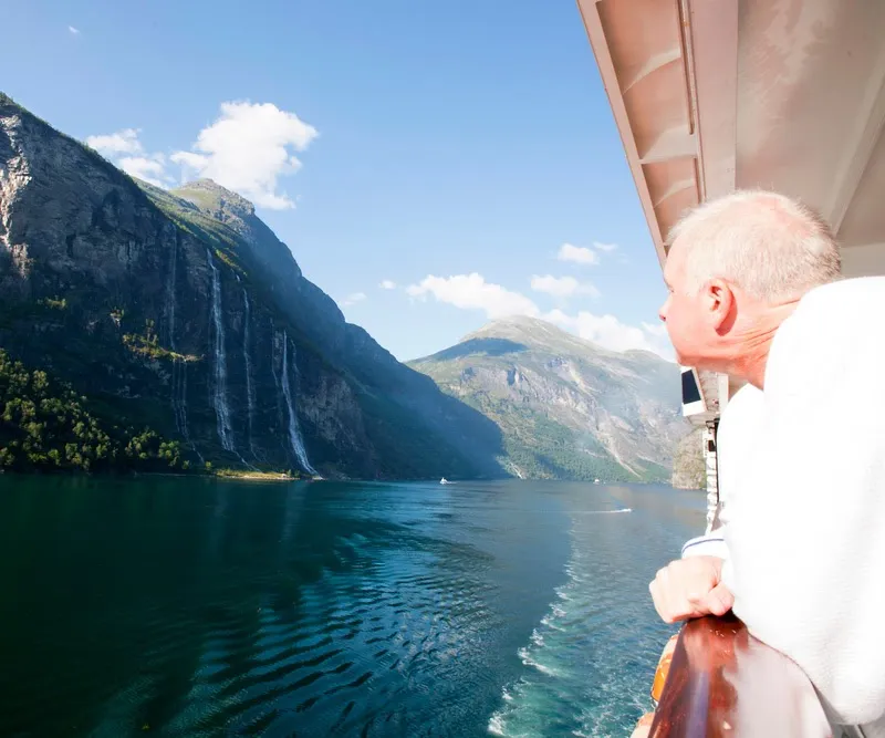Ein Reisender genießt den majestätischen Geirangerfjord während einer sommerlichen Küstenreise