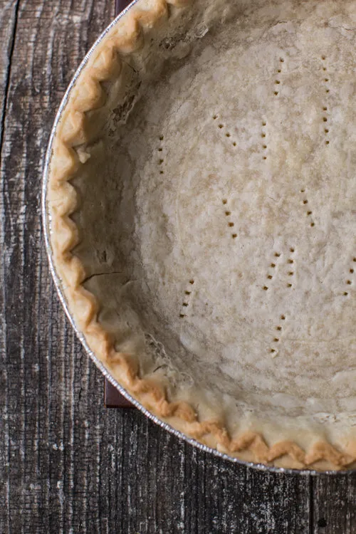 Ein roher, runder Tortenboden in einer Backform, bereit zum Vorbacken.