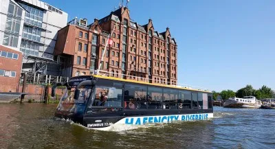 Ein roter Doppeldeckerbus, der als Amphibienfahrzeug auf der Elbe in Hamburg fährt