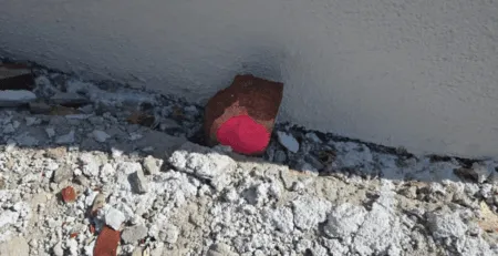 Ein roter Stein mit einem pinken Punkt auf grauem Untergrund