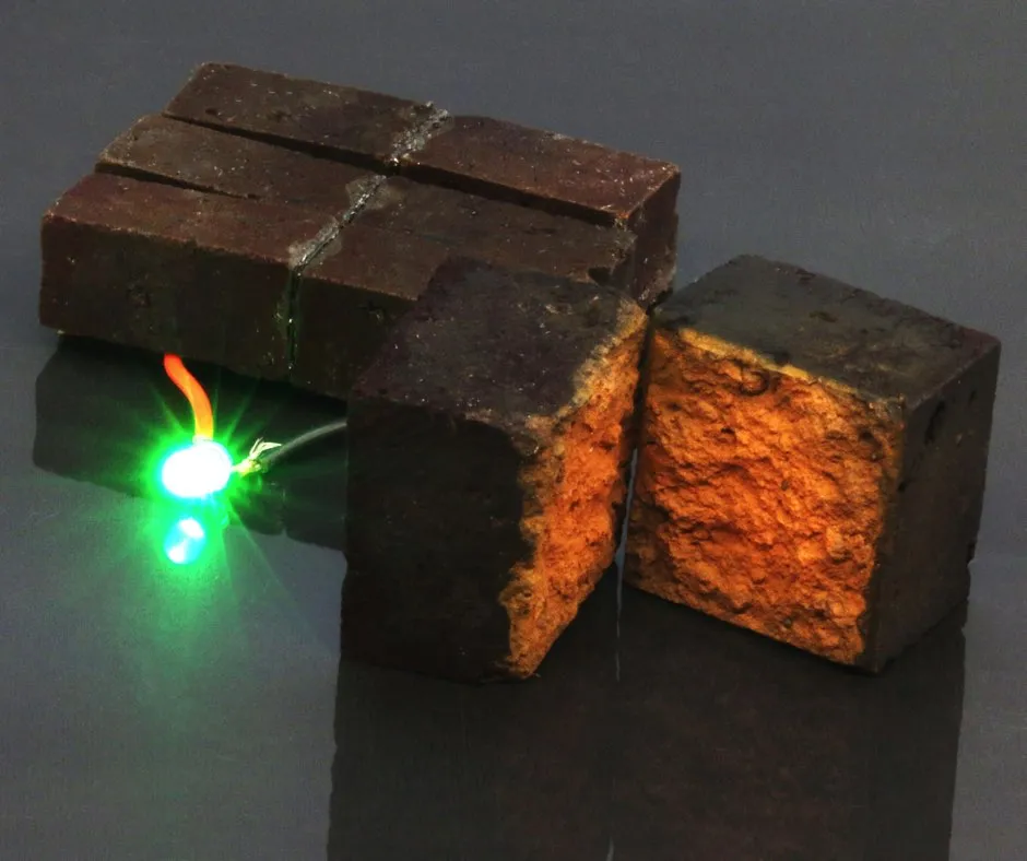 Ein roter Ziegelstein, der an eine grüne LED angeschlossen ist und diese leuchten lässt