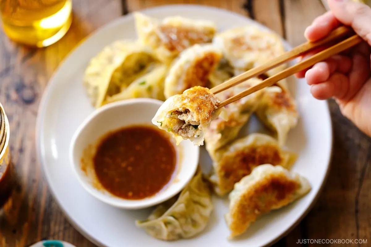 Ein runder Teller mit Napa Cabbage Gyoza, serviert mit einer herzhaften Miso-Dip-Sauce.